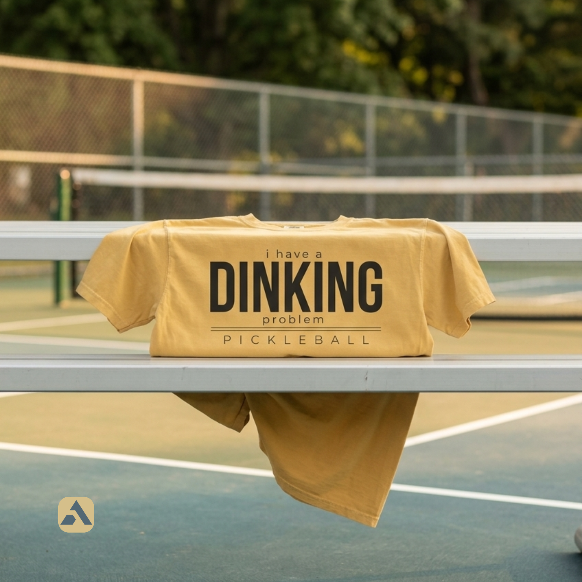 I Have a Dinking Problem pickleball t-shirt, Mustard — draped over a bench