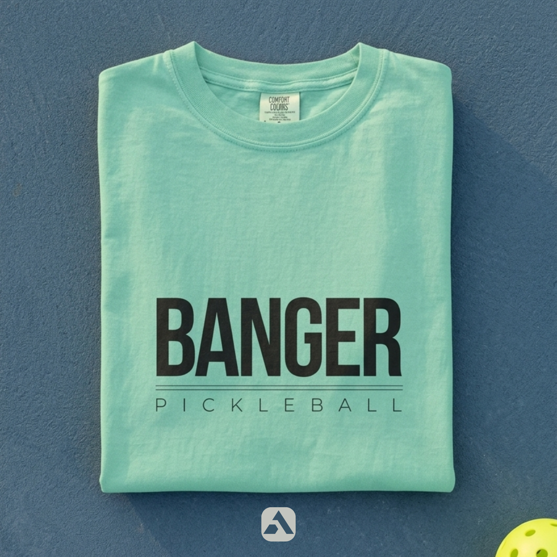 Banger pickleball t-shirt, Island Reef — folded flat-lay with ball