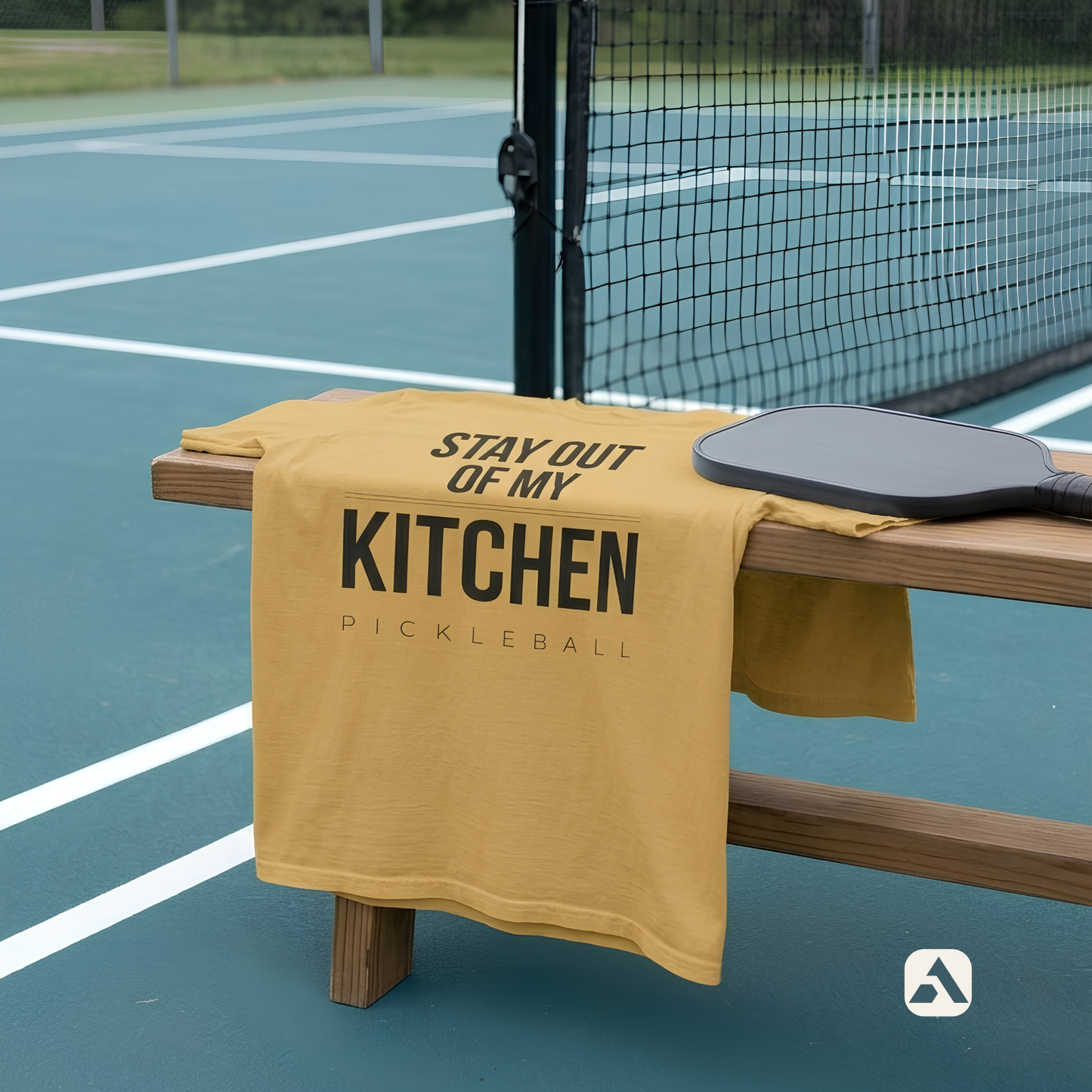 Stay Out of My Kitchen pickleball t-shirt, Mustard — draped over a bench